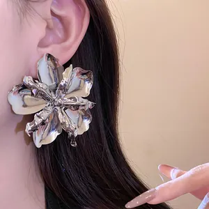 Detailed view of oversized metallic silver flower stud earring with liquid texture.