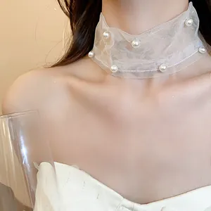 Dettaglio ravvicinato di un girocollo in mesh bianco con perle eleganti su una modella
