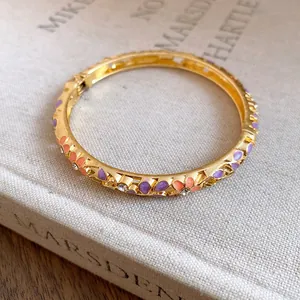 Detailed view of a gold-plated bangle featuring colorful enamel flowers and sparkling crystals
