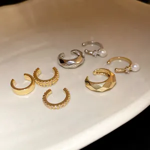 Macro view of elegant gold and silver zircon ear cuffs displayed on a ceramic tray