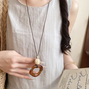 Detail of a minimalist amber resin oval pendant necklace with a long leather cord