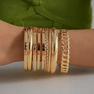 Detalle de un conjunto de 10 brazaletes geométricos de metal dorado lucidos en la muñeca