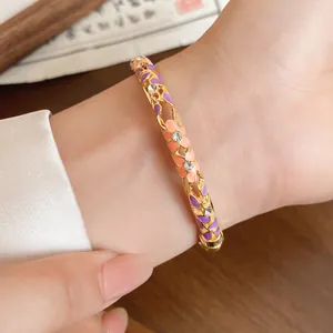 Close-up detail of a gold floral bangle with purple enamel and inlaid crystals
