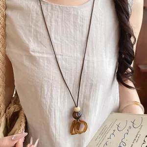 Macro detail of a minimalist resin oval pendant necklace on a long brown leather cord.