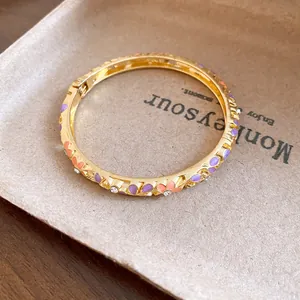 Macro detail view of a vintage gold floral bangle with purple enamel and clear crystals