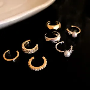 Assorted minimalist zircon and pearl ear cuffs for non-pierced ears on a dark background