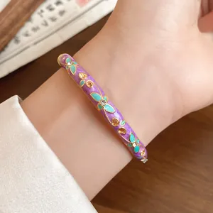 Close-up of a vintage purple enamel flower bangle with rhinestone details on a wrist