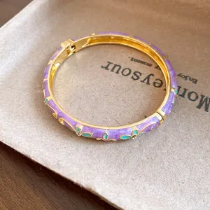 Macro detail of retro gold bangle with purple enamel flowers and sparkling rhinestones.
