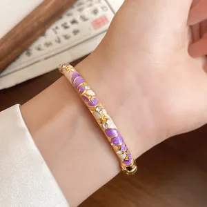 Close-up detail of vintage gold bangle with purple enamel and sparkling rhinestones on wrist