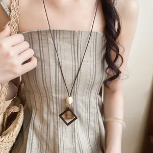 Close-up detail of a minimalist geometric resin pendant necklace on a model wearing stripes