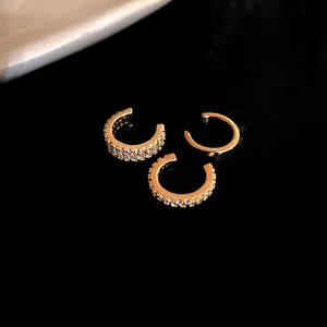 Close-up of three gold ear cuffs featuring paved zircons and a minimalist smooth finish