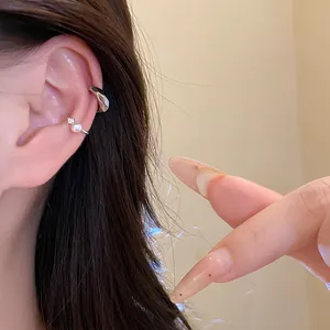 Detailed view of silver-tone ear cuffs with pearl and zircon accents on a model's ear