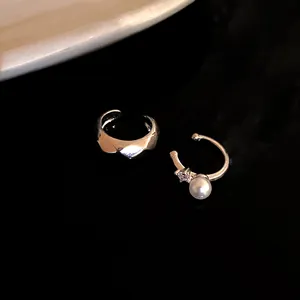 Close-up view of minimalist silver non-pierced ear cuffs featuring pearl and zircon accents