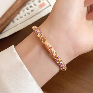 Detail of a vintage gold-toned bangle with pink and purple enamel flowers and crystals.