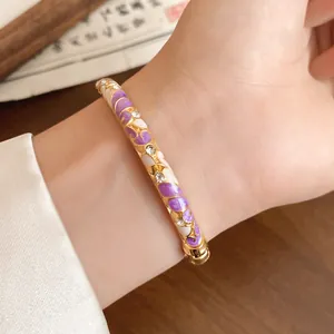Close-up detail of vintage gold-plated bangle with purple enamel floral and rhinestones