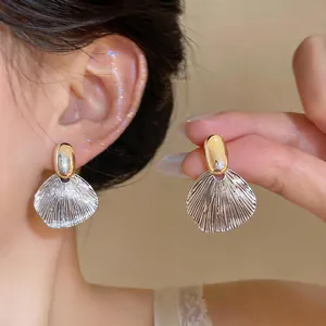 Detailed view of French-style textured leaf earrings in silver and gold tone metal