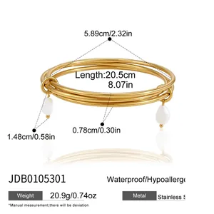 Detailed view of gold multi-layer stainless steel bangle set with pearl charms.