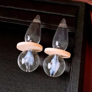 Vintage minimalist transparent teardrop earrings with wood accent on a black velvet tray