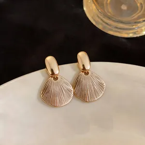 Close-up of elegant gold textured leaf drop earrings with a polished metallic finish