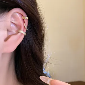 Close-up detail of three gold-plated ear cuffs with cubic zirconia worn on a female ear