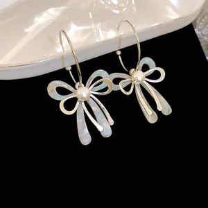 Detailed close-up of elegant bow-shaped earrings with lustrous pearls and iridescent finish