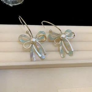 Close-up of elegant bowtie earrings with pearls and iridescent accents on a velvet display