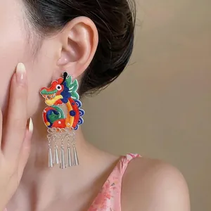 Handcrafted ethnic style dragon embroidered earring with silver tassels worn on ear