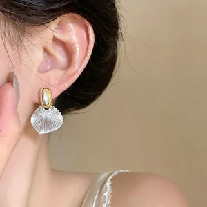 Close-up detail of French style textured leaf earrings with gold and silver finish