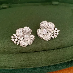 Detailed macro view of silver needle flower stud earrings with sparkling zircons.