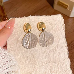 Detailed close-up of French style textured leaf stud earrings in gold and silver finish.