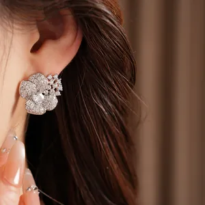 Elegant flower-shaped stud earring paved with shimmering cubic zirconia shown on ear