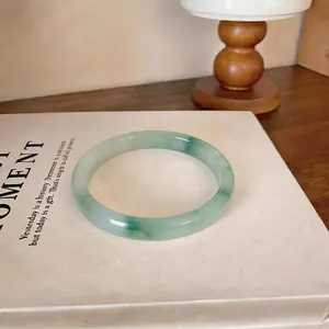 Gros plan d'un bracelet en calcédoine translucide effet lavis vert posé sur un livre