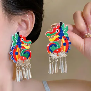 Detailed view of vibrant embroidered dragon earrings featuring elegant silver-tone tassels