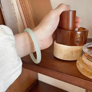 Gros plan élégant d'un bracelet jonc en calcédoine blanche translucide sur un poignet féminin.