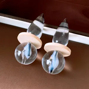 Close-up of vintage transparent teardrop earrings with wood disc and blue inner pattern