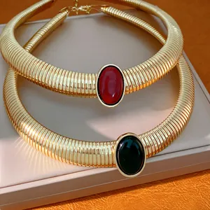 Dettaglio delle collane choker dorate con eleganti pietre ovali in resina rossa e nera