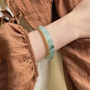 Gros plan d'un bracelet en calcédoine translucide avec des motifs verts sur un poignet.