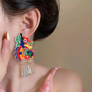 Detailed view of vibrant ethnic dragon embroidered earrings with silver tassels on ear