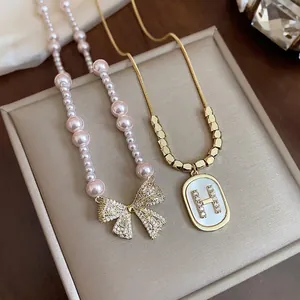 Elegant pearl necklace with zircon bow and gold chain with mother of pearl letter H