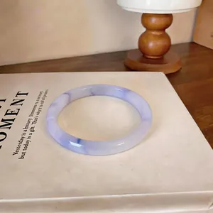 Gros plan détaillé du bracelet en calcédoine translucide violet clair sur un livre