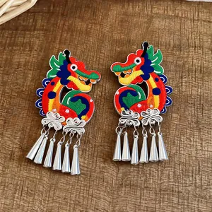 Detailed shot of ethnic style knitted dragon clip earrings with silver tassel pendants.