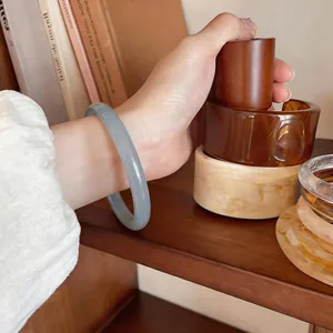 Gros plan d'un élégant bracelet en calcédoine gris glacé porté au poignet sur bois