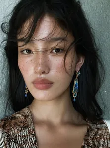Detail shot of Asian model wearing vintage blue resin flower drop earrings with rhinestones