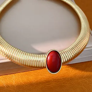 Dettaglio di girocollo dorato con un grande inserto centrale in resina rossa ovale