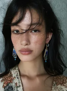 Close-up of model wearing vintage blue floral enamel dangle earrings in royal court style