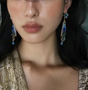 Close-up of vintage royal court style resin flower earrings with blue rhinestones