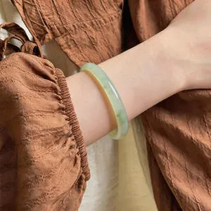 Gros plan détaillé d'un bracelet en calcédoine vert clair translucide sur le poignet d'une femme.