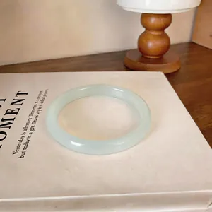 Gros plan d'un élégant jonc en calcédoine blanche translucide sur un livre épuré
