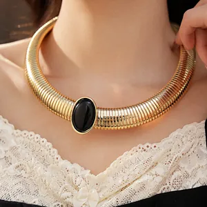 Dettaglio di una collana girocollo dorata con un grande inserto ovale in resina nera
