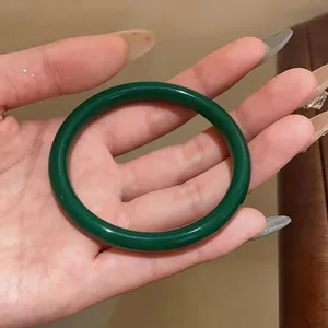 Gros plan détaillé montrant la texture translucide d'un bracelet jonc en calcédoine vert foncé